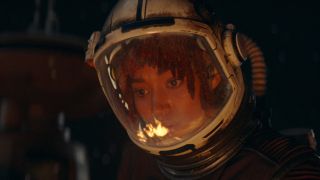 Amandla Sternberg's Osha looking at a fire while repairing the outside of a ship in The Acolyte